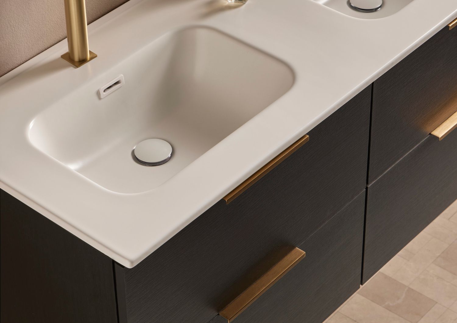 Detalle de lavabo integrado blanco con encimera sobre mueble de baño en madera oscura de la colección NOAH.