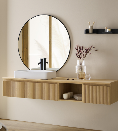 Mueble de baño de la serie ARBON con diseño curvo, acabado en madera acanalada y espejo redondo.
